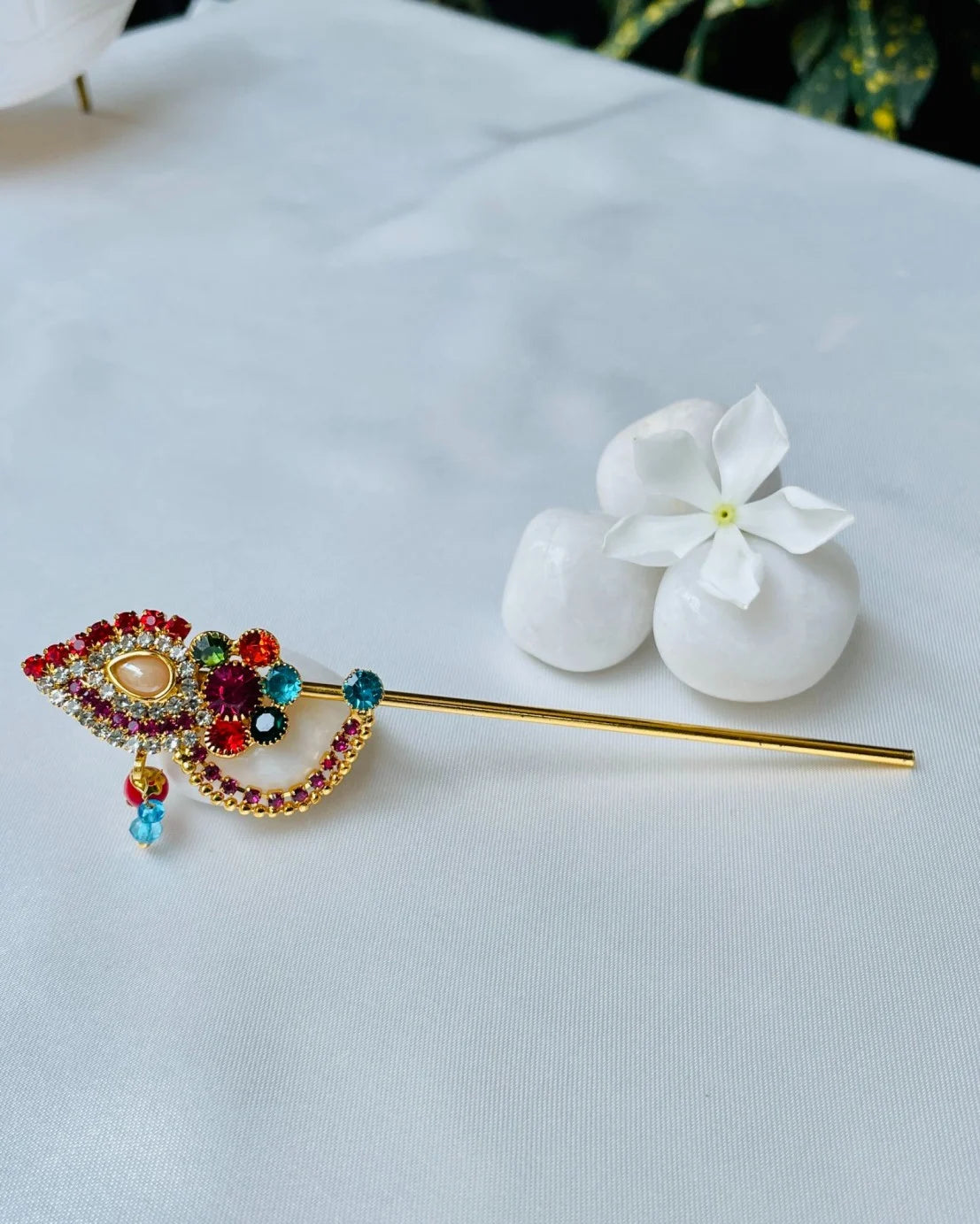 Red and gold crystal-studded Laddu Gopal bansuri with floral centerpiece and hanging beads – divine flute for Kanha Ji shringar.