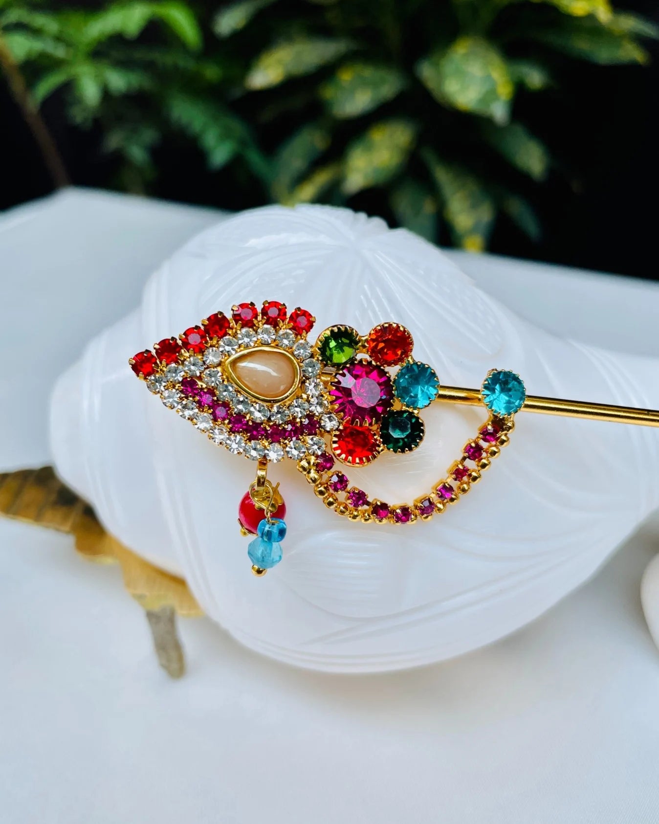 Red and gold crystal-studded Laddu Gopal bansuri with floral centerpiece and hanging beads – divine flute for Kanha Ji shringar.