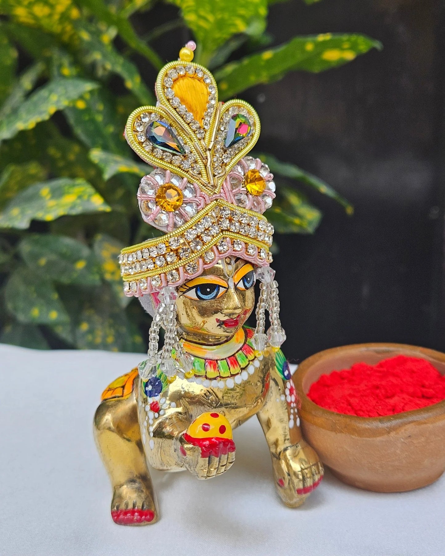 Golden and pink Laddu Gopal Mukut with kundan stones, crystal beads, and pearl tassels – elegant crown for Kanha Ji shringar.