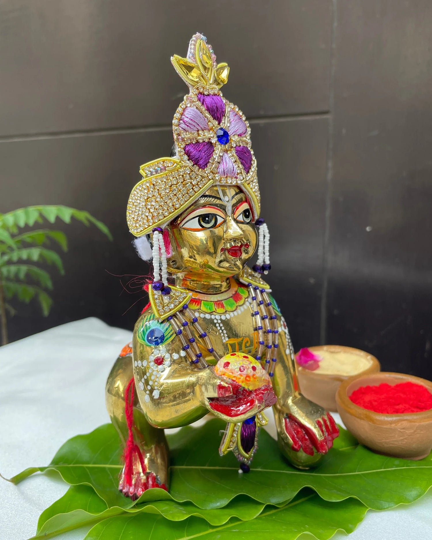 Bal Gopal idol wearing a purple embroidered mukut and layered mala – elegant Laddu Gopal jewellery set for pooja and festive shringar.