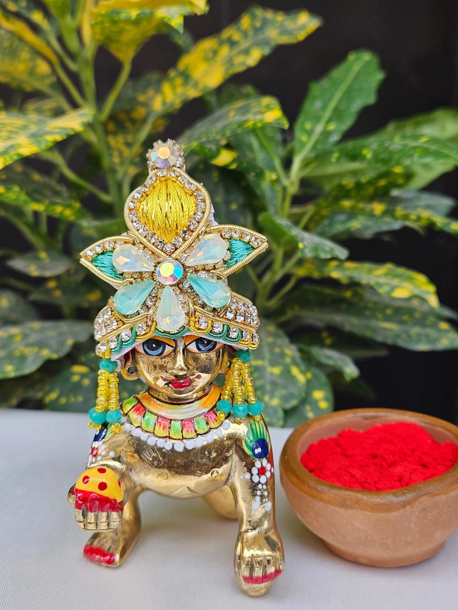 Laddu Gopal Mukut with yellow floral design, aqua blue accents, and stone embellishments for Kanha Ji idol.