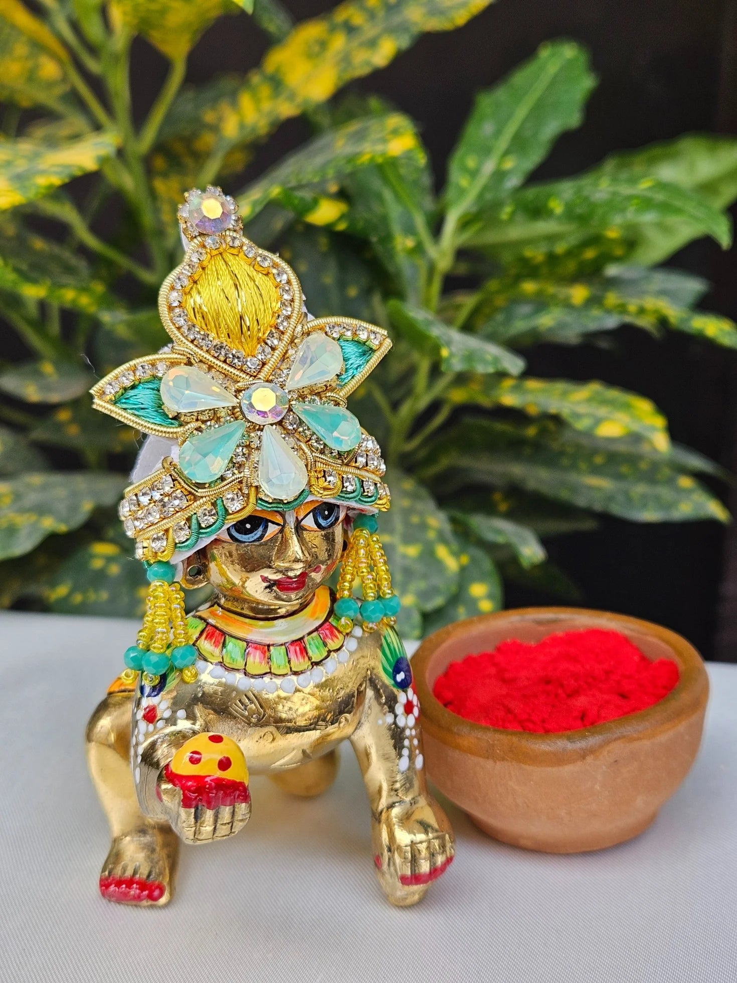 Laddu Gopal Mukut with yellow floral design, aqua blue accents, and stone embellishments for Kanha Ji idol.