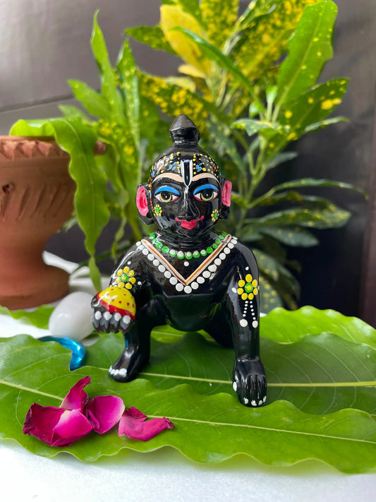 Black Laddu Gopal Vigraha idol holding a laddu – hand-painted brass murti with devotional detailing.
