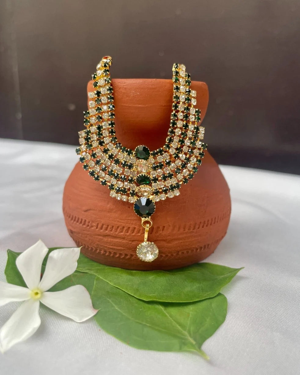 Laddu Gopal 4-layer green and white stone jewellery haar placed on terracotta pot with leaves and white flower.
