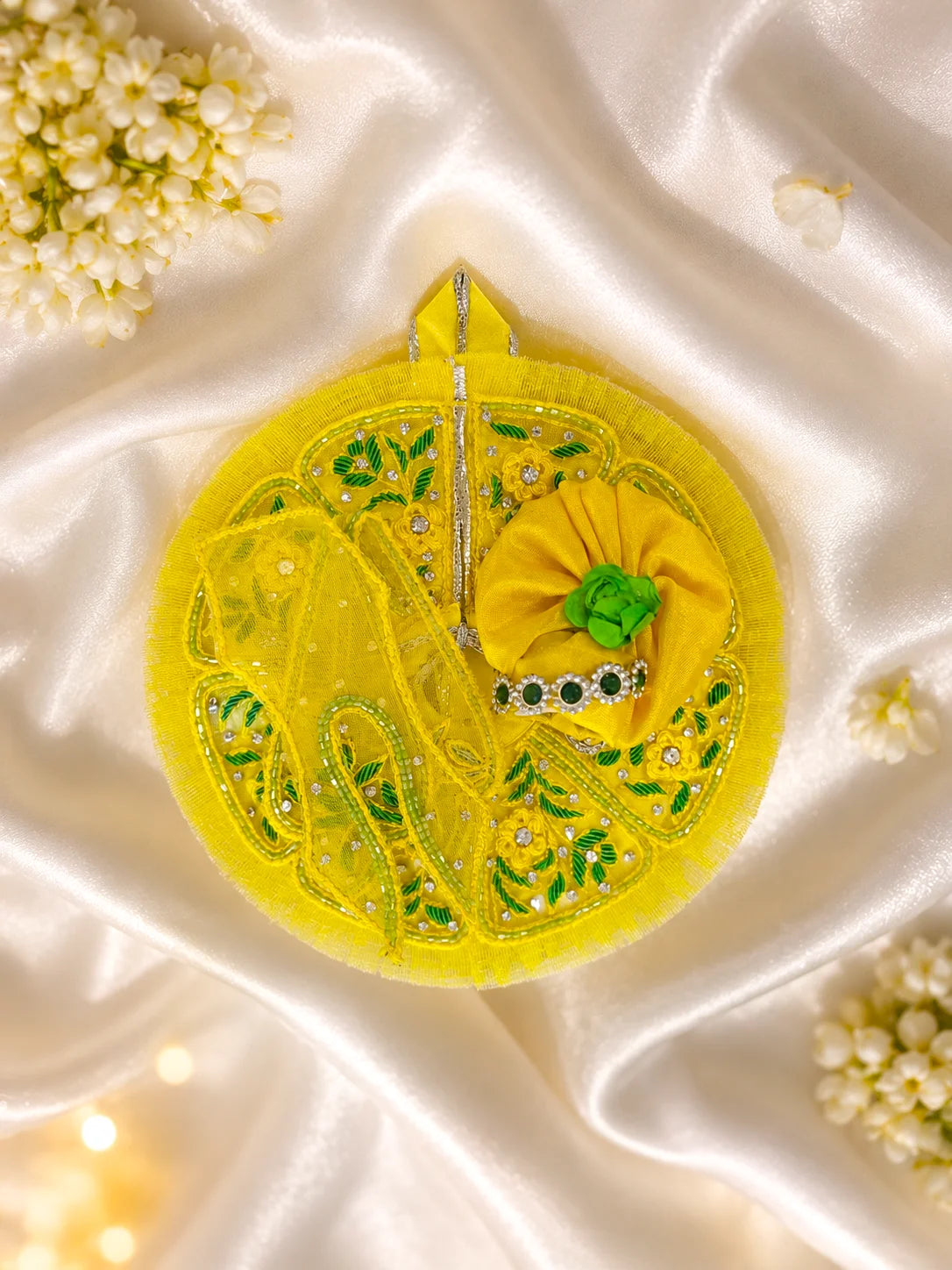 Black stone Laddu Gopal Ji idol adorned in a premium bright yellow dress with green leaf embroidery, sparkling stone work, and a matching heavy yellow turban decorated with green fabric roses
