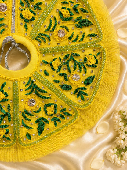 Black stone Laddu Gopal Ji idol adorned in a premium bright yellow dress with green leaf embroidery, sparkling stone work, and a matching heavy yellow turban decorated with green fabric roses