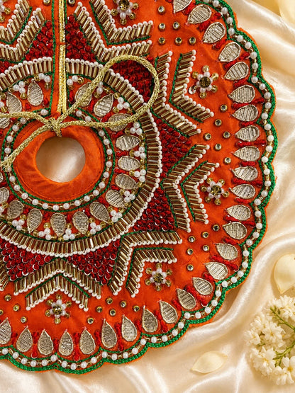 Vibrant orange festive Laddu Gopal poshak set with intricate white pearl beadwork, heavy zardozi embroidery, matching patka, and decorated turban displayed flat on white silk