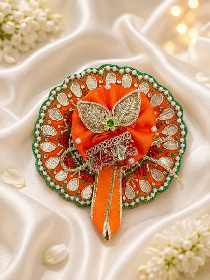 Vibrant orange festive Laddu Gopal poshak set with intricate white pearl beadwork, heavy zardozi embroidery, matching patka, and decorated turban displayed flat on white silk