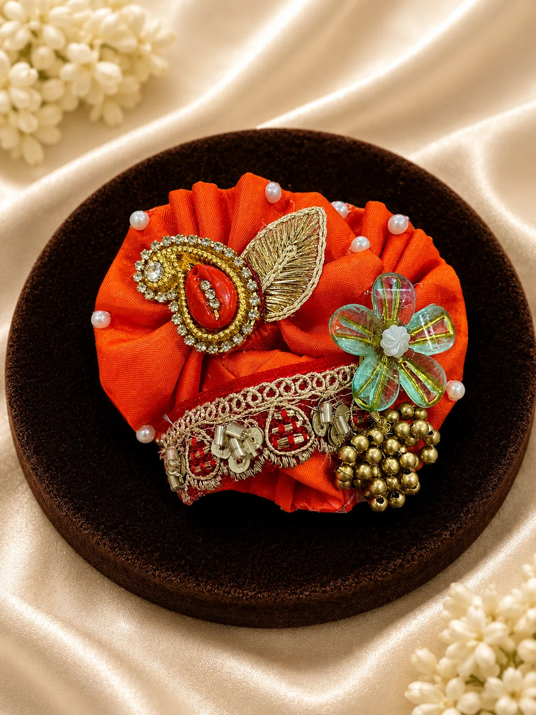 Vibrant orange festive Laddu Gopal poshak set with intricate white pearl beadwork, heavy zardozi embroidery, matching patka, and decorated turban displayed flat on white silk