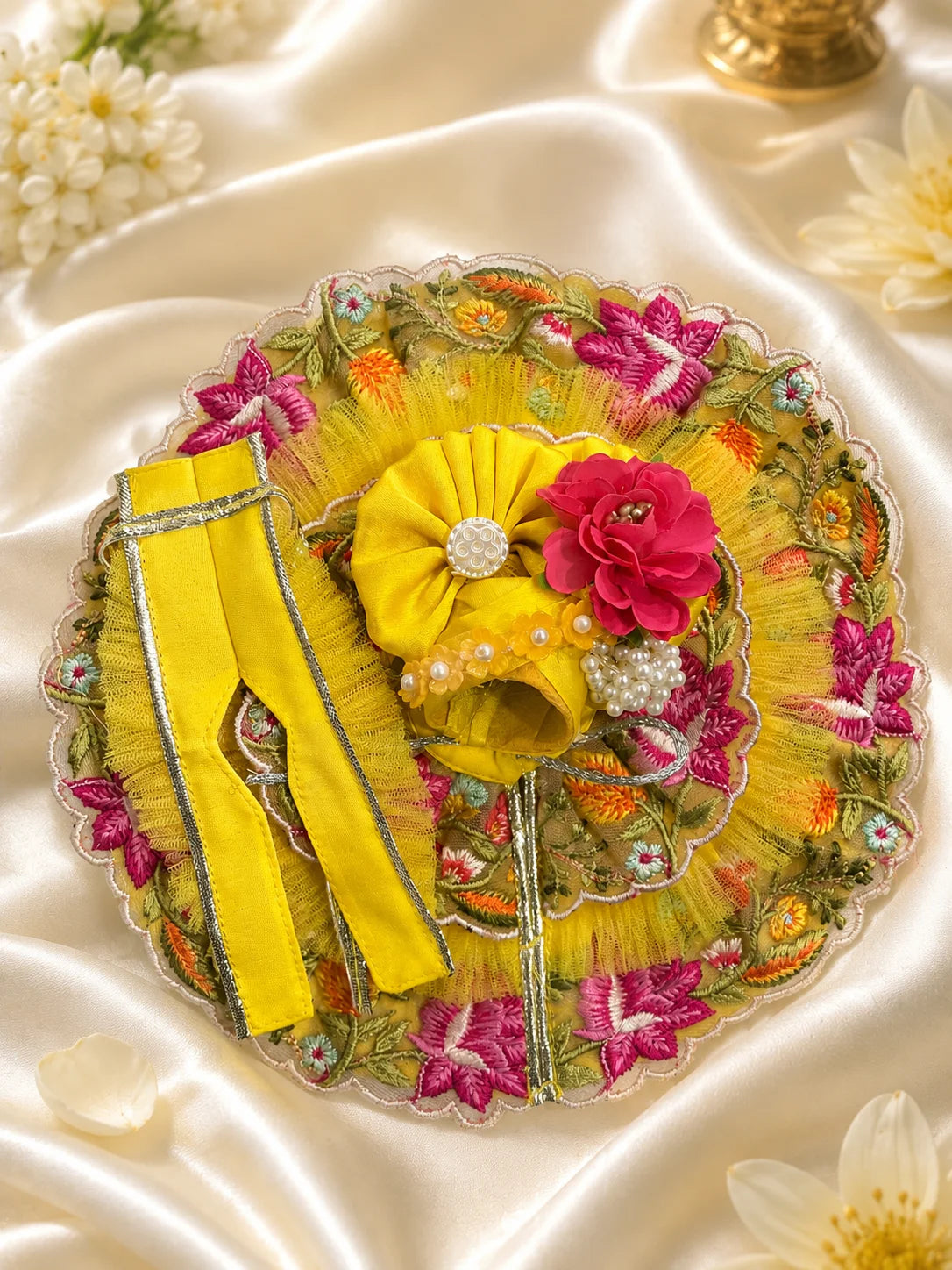 Black stone Laddu Gopal Ji idol wearing a premium yellow double-layered dress with multi-color magenta and orange floral embroidery, silver scalloped lace, and a matching yellow turban decorated with a heavy magenta fabric rose