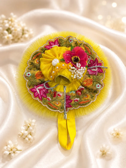 Black stone Laddu Gopal Ji idol wearing a premium yellow double-layered dress with multi-color magenta and orange floral embroidery, silver scalloped lace, and a matching yellow turban decorated with a heavy magenta fabric rose