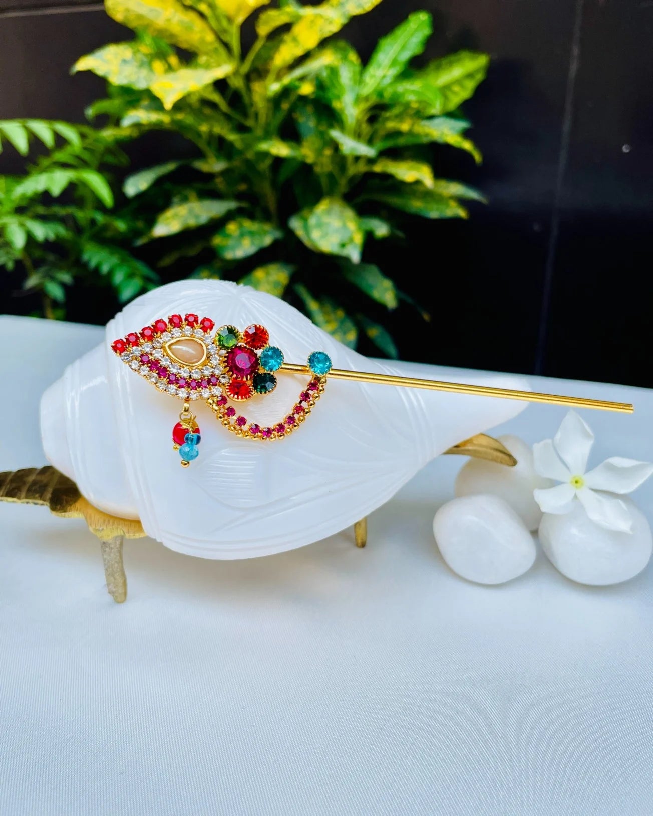 Red and gold crystal-studded Laddu Gopal bansuri with floral centerpiece and hanging beads – divine flute for Kanha Ji shringar.
