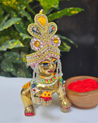 Golden and pink Laddu Gopal Mukut with kundan stones, crystal beads, and pearl tassels – elegant crown for Kanha Ji shringar.