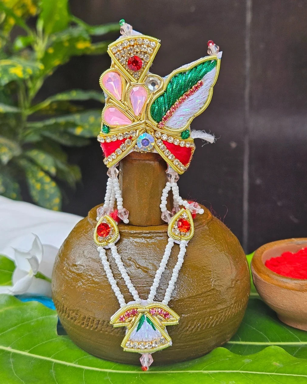 Laddu Gopal red green feather mukut with white bead mala – crown and necklace set for Krishna shringar.