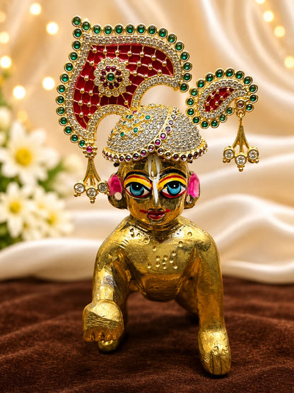 Manikya Panna Rajmahal AD Mukut for Deity featuring ruby-red and emerald-green inspired jewel detailing, royal palace-inspired ornamentation and sparkling American Diamond work for Laddu Gopal shringar.

