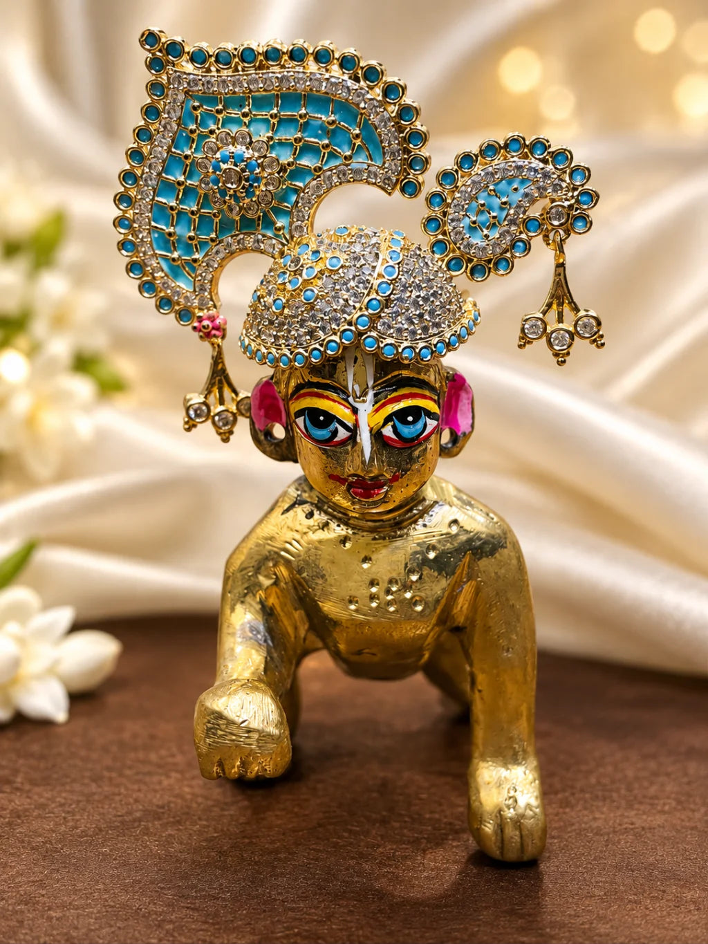 Manikya Panna Rajmahal AD Mukut for Deity featuring ruby-red and emerald-green inspired jewel detailing, royal palace-inspired ornamentation and sparkling American Diamond work for Laddu Gopal shringar.
