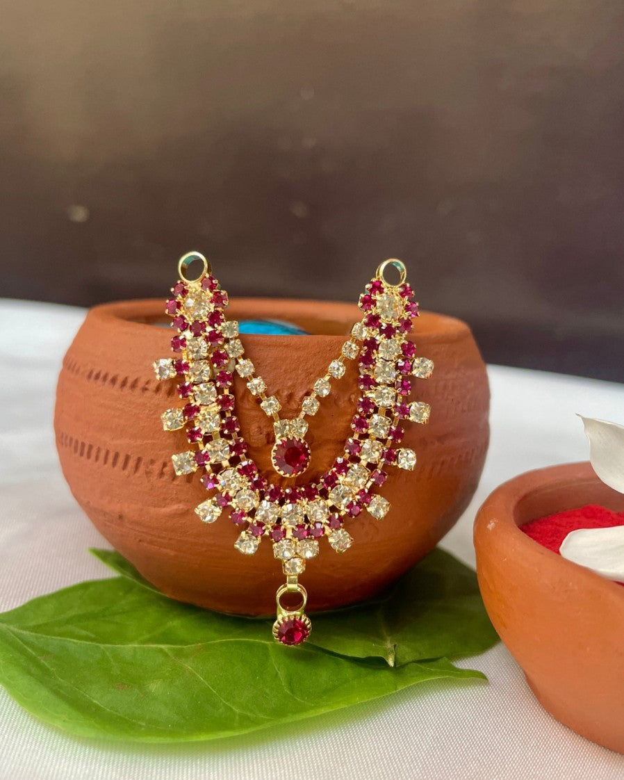 Double-layer pink and white stone Laddu Gopal haar placed on terracotta pot with green leaf and red kumkum.