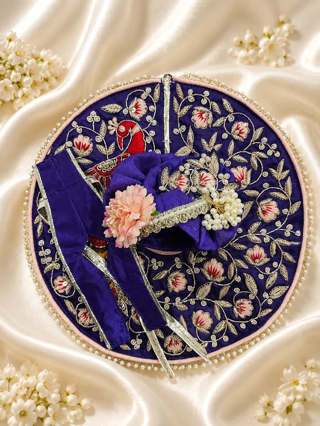 Royal purple Laddu Gopal dress set with detailed silver embroidery, embroidered peacock motif, pearl border, matching patka, and pink flower pagdi turban on white silk fabric