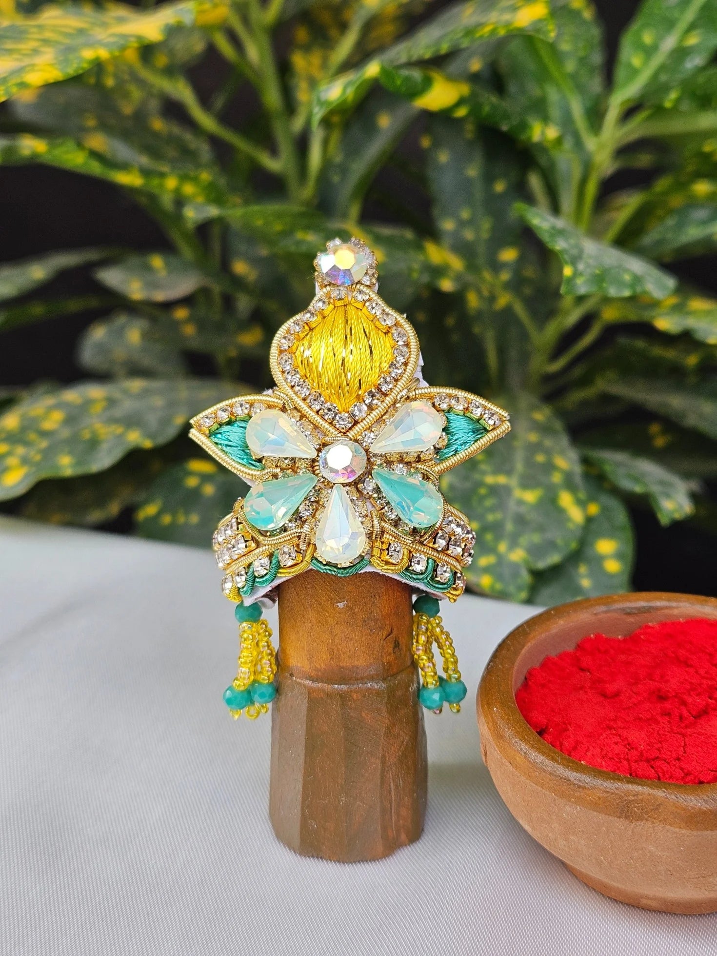 Laddu Gopal Mukut with yellow floral design, aqua blue accents, and stone embellishments for Kanha Ji idol.