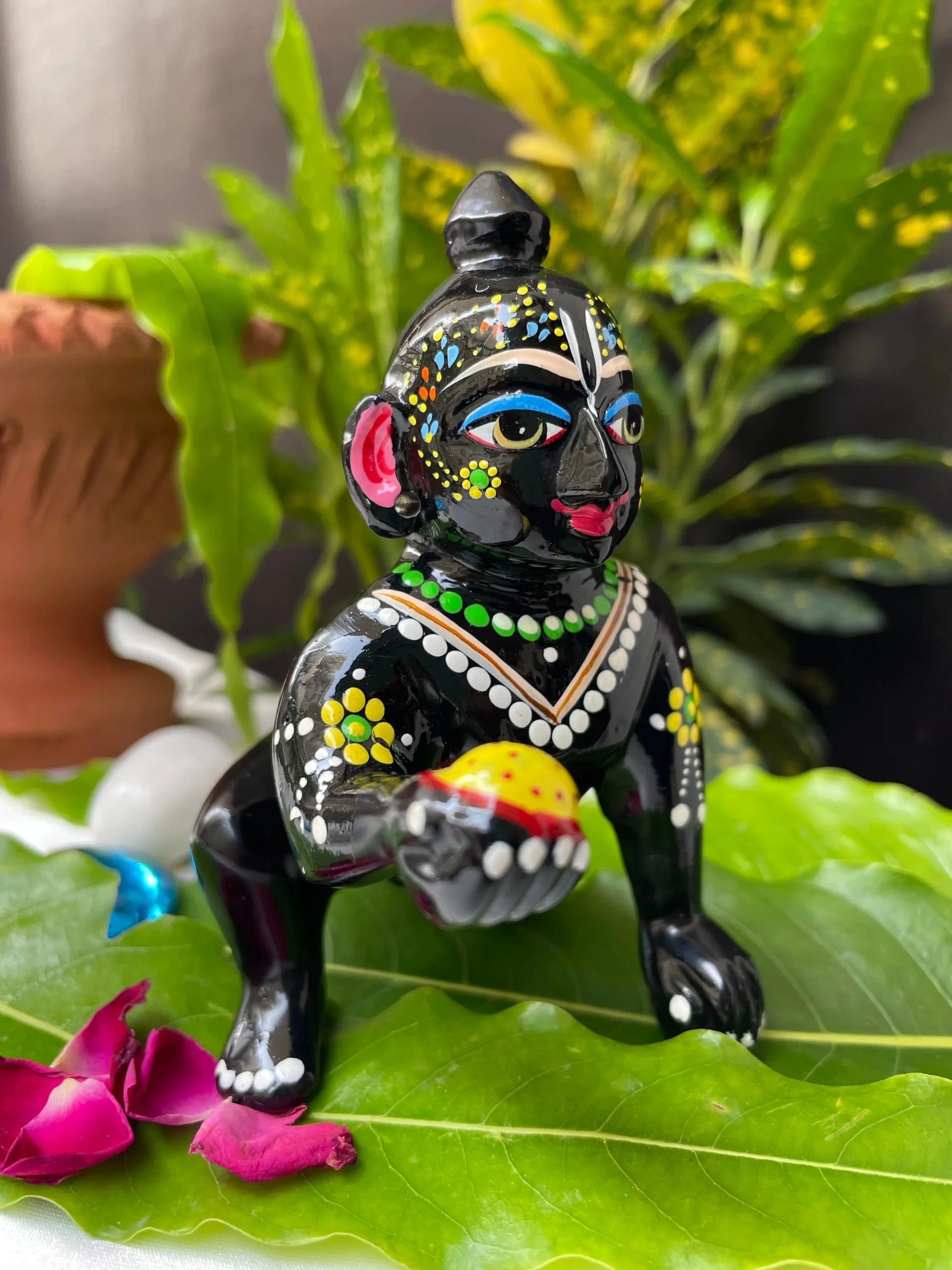 Black Laddu Gopal Vigraha idol holding a laddu – hand-painted brass murti with devotional detailing.