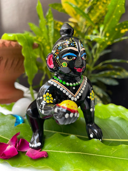 Black Laddu Gopal Vigraha idol holding a laddu – hand-painted brass murti with devotional detailing.