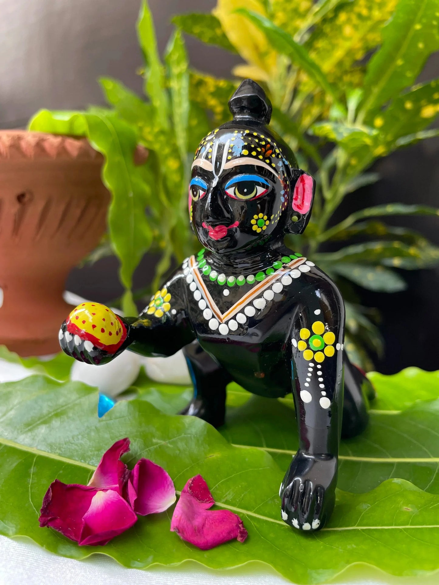 Black Laddu Gopal Vigraha idol holding a laddu – hand-painted brass murti with devotional detailing.
